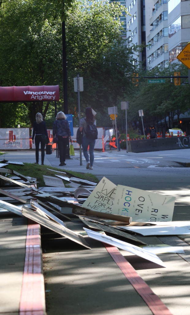 A vertical long shot of a sidewalk with signs on the ground.